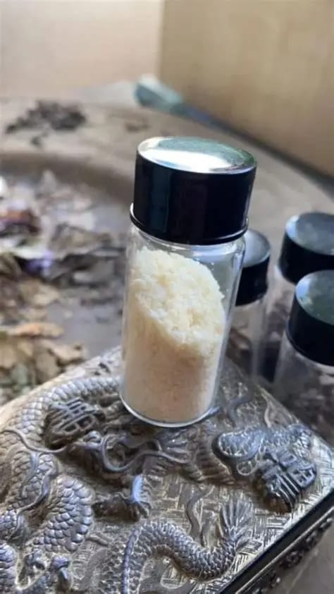 Small transparent plastic container sealed shut, holding a whitish, resin-like substance labeled as Bufo alvarius venom, photographed against a neutral background.